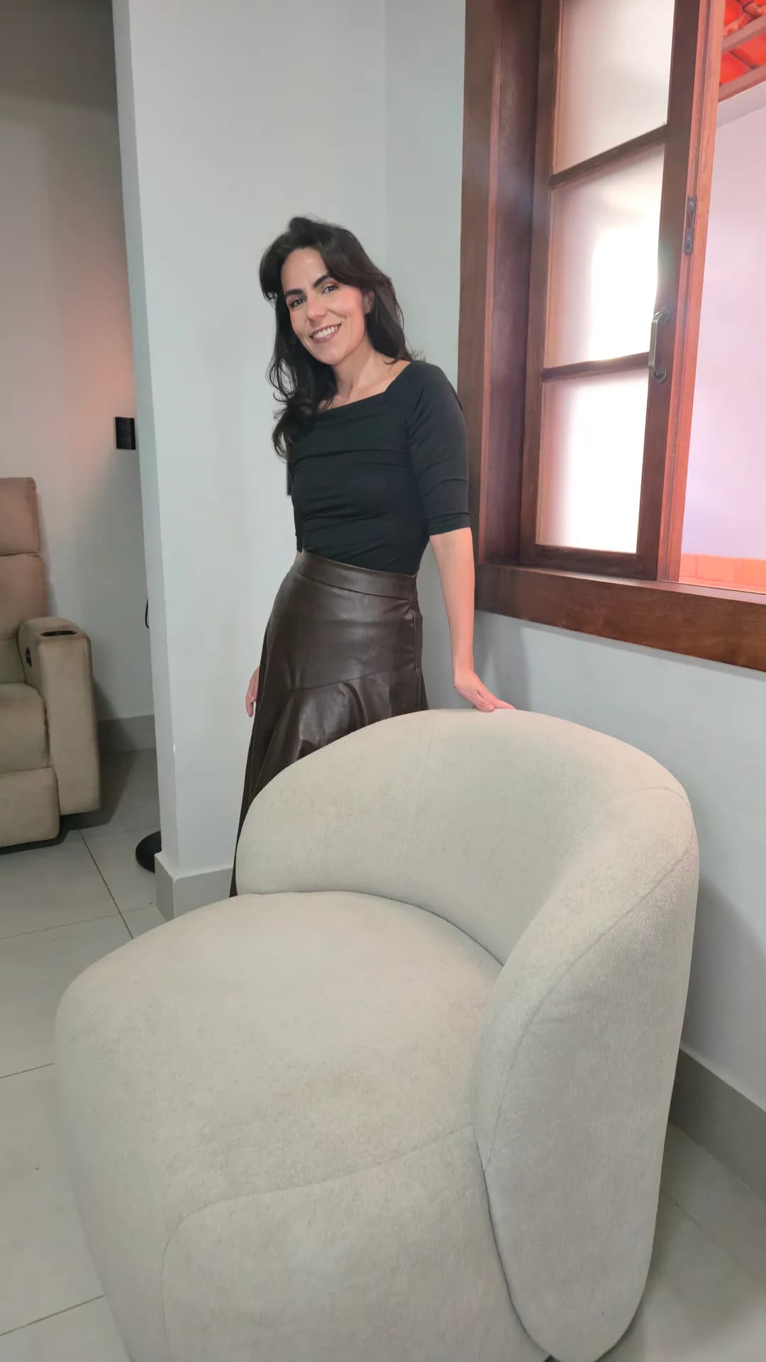 Cecília em pé ao lado da Poltrona Moon Damie vista de perfil.