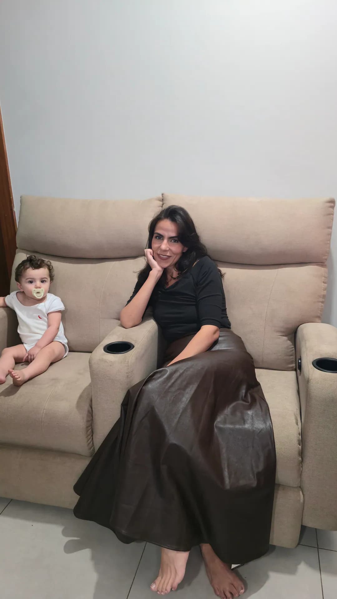 Cecília relaxando em uma Poltrona Reclinável Damie bege na sala de casa.