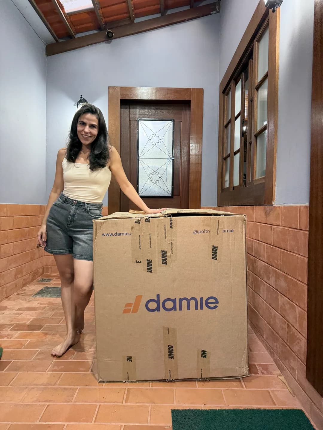 Cecília em pé ao lado da caixa recém-entregue da Poltrona Reclinável Damie 2.0