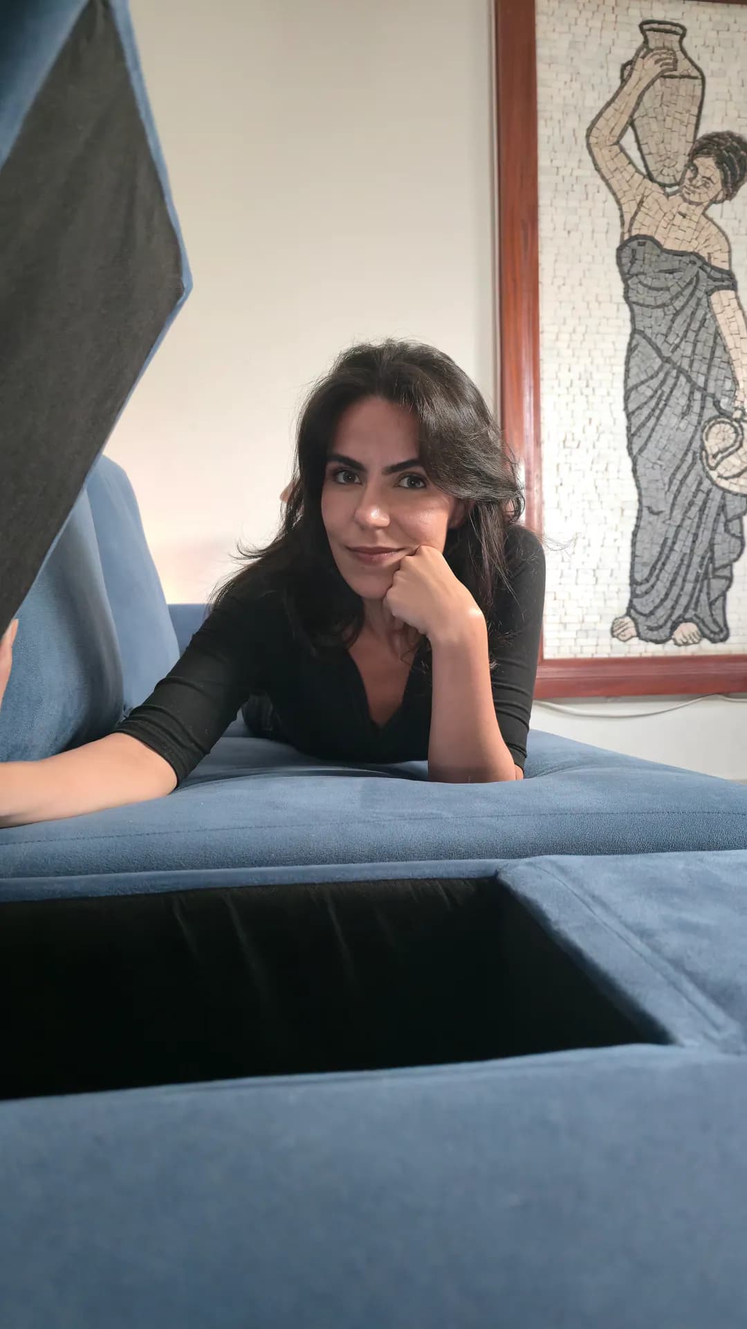 Cecília mostrando o compartimento interno aberto de um módulo com baú do Sofá Modular Damie.